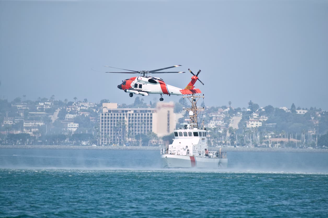 Coast Guard helicopter and patrol vessel conducting coastal security and defense operations